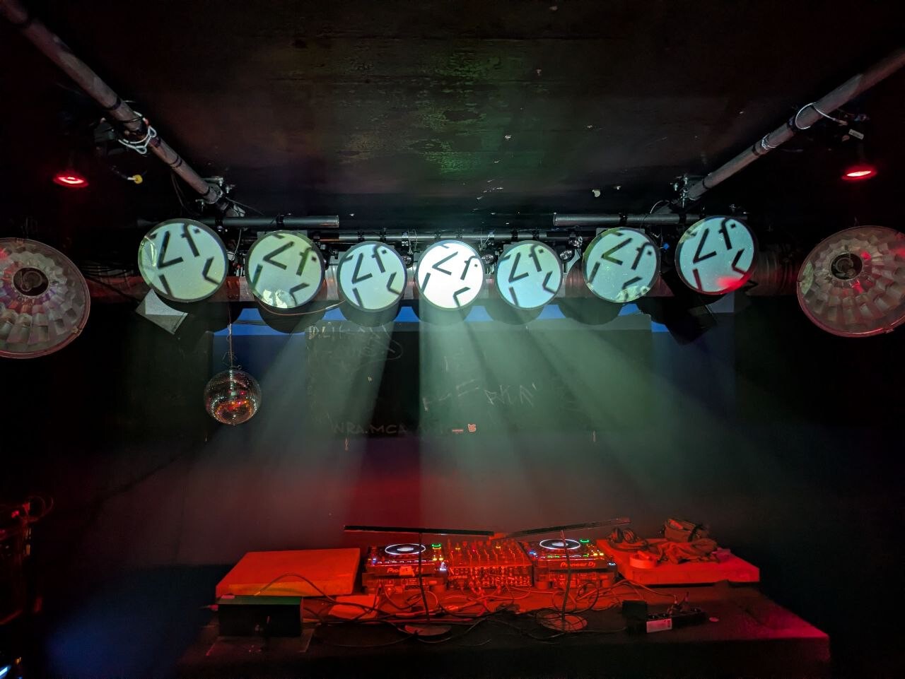 Dancefloor vom Bunker mit Blick auf das DJ-Pult. Über dem DJ-Pult eine Reihe Runderlichter mit der Projektion 'ZfK' drauf in weiß/blau
